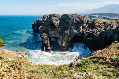 Rock formation on sea shore against sky