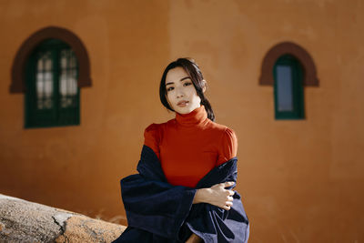 Portrait of woman standing against building