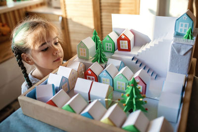 Origami advent calendar, paper craft. girl looking upon paper houses with number and paper tree