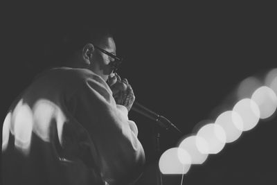 Side view of a young man playing in the dark