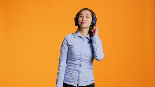 Young woman standing against yellow wall