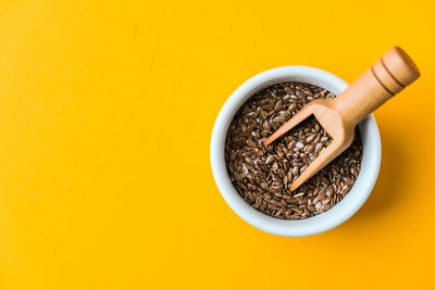 Wooden spoon with flax seeds lies in a white mortar on a yellow background. healthy eating. keto