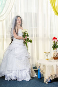 Midsection of woman holding flower bouquet against wall