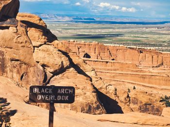 Information sign on rock formation against sky