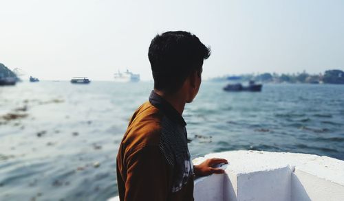 Rear view of man looking at sea against sky