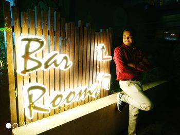 Portrait of smiling man standing by illuminated text