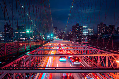 Light trails on road amidst buildings against sky at night