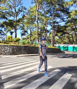 Full length of man standing on road against trees