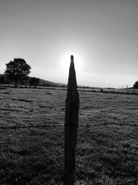 Wooden posts on field against sky at sunset