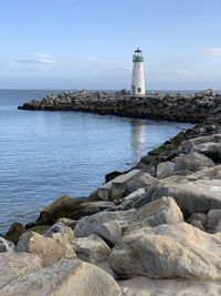 Lighthouse by sea against sky