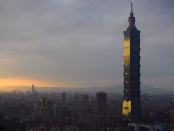 Skyscrapers in city against cloudy sky