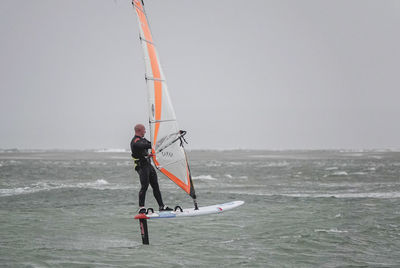 Man surfing in sea against sky