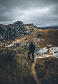 Rear view of man standing on land against sky