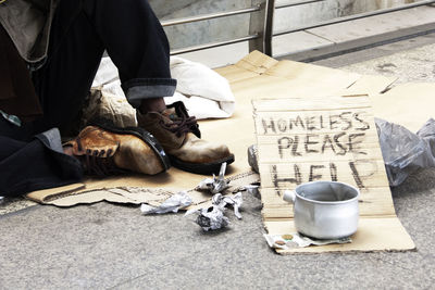 Low section of homeless beggar sitting on footpath