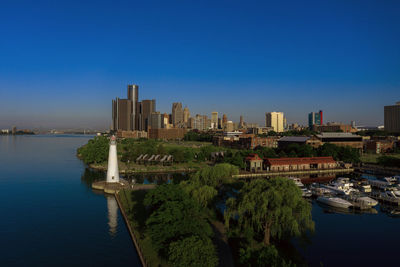 Scenic view of river by buildings against clear blue sky