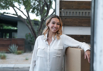 Portrait of smiling woman standing against built structure