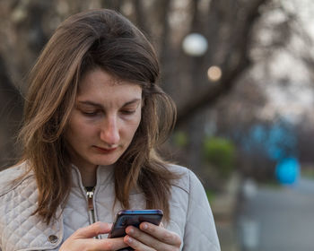 Portrait of teenage girl using mobile phone outdoors