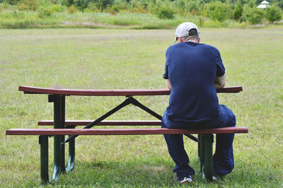 Rear view of woman sitting on bench in park