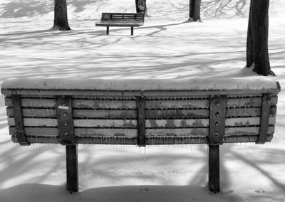 Empty bench in snow covered park during winter