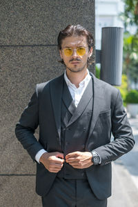 Portrait of young man standing against wall