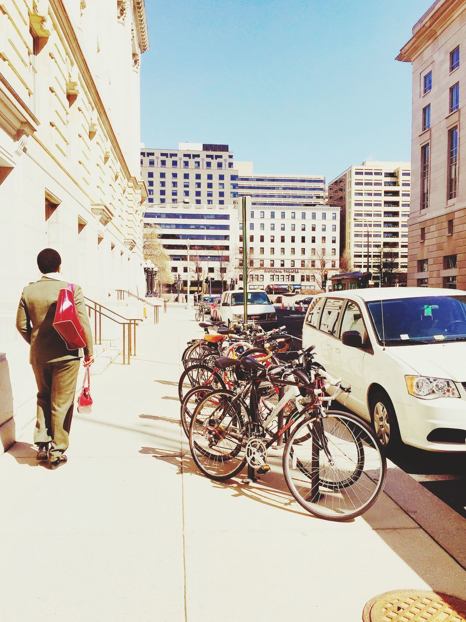 architecture, building exterior, built structure, clear sky, city, residential structure, residential building, street, bicycle, building, men, day, city life, wall - building feature, walking, outdoors, sunlight, lifestyles