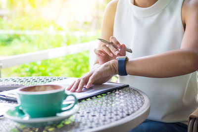 Midsection of woman holding coffee cup on table