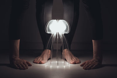 Low section of man standing on floor in illuminated room