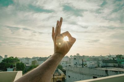 Close-up of man with cityscape against sky during sunset