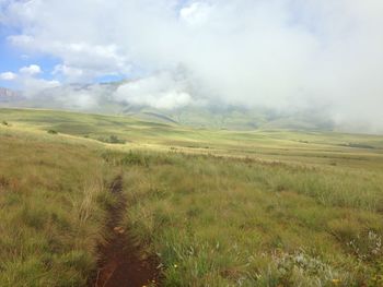 Scenic view of grassy field against cloudy sky