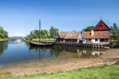 Houses by river and buildings against sky