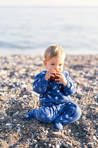 Cute baby boy on pebbles at beach