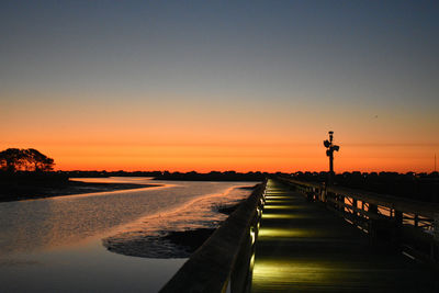 Road by sea against clear sky during sunset