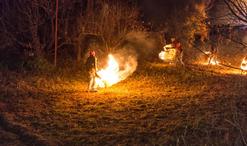 People by fire in forest at night