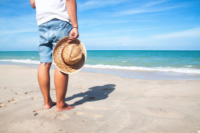 Low section of person on beach against sea