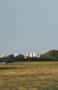 Buildings on field against clear sky