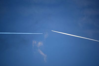 Low angle view of vapor trails against blue sky