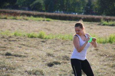 Smiling young woman holding thread on field