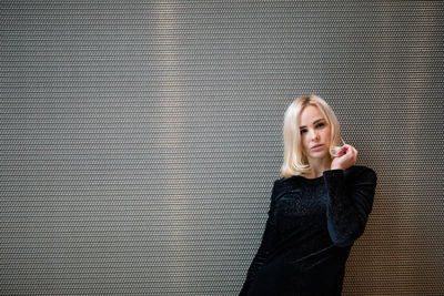 Portrait of beautiful woman standing against metallic wall