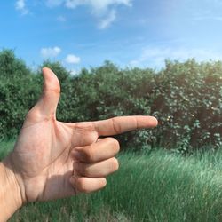 Cropped image of hand gesturing against trees