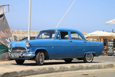 Side view of vintage car on road against blue sky