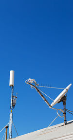 Low angle view of telephone pole against clear blue sky