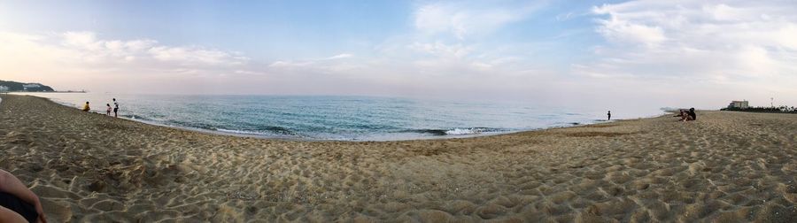 Panoramic view of people on beach against sky