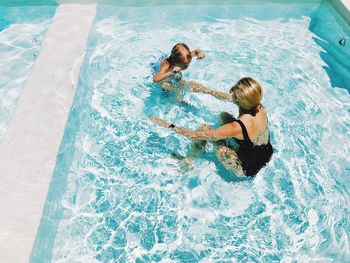 High angle view of woman with daughter swimming in pool 