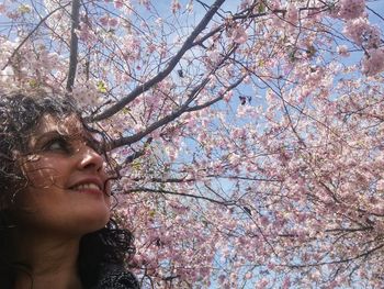 Close-up of smiling woman looking at cherry tree