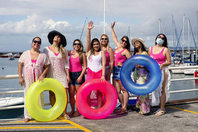 Women standing with their arms up in a bikini with beach accessories. 