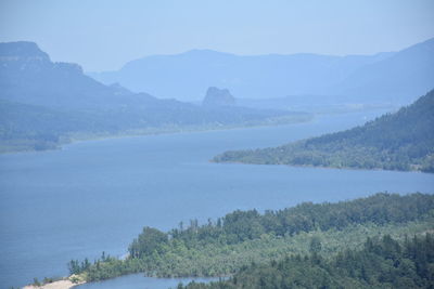 Scenic view of river by mountains against clear sky