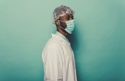 Doctor wearing mask standing against blue background