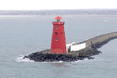 Lighthouse by sea against sky