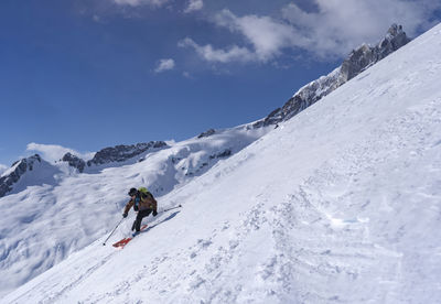 Man skiing on snowcapped mountain against sky