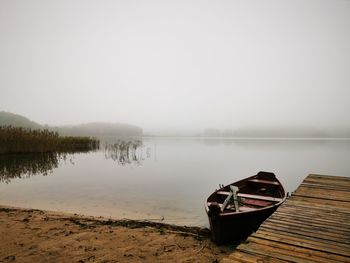 Boat moored on lake against sky